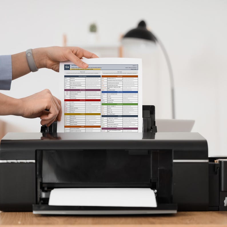 Mockup image showing a printable Python Cheat Sheet page being placed into a printer. The image demonstrates the print-ready nature of the PDF file, designed for offline study, desk reference, and quick access to Python syntax and concepts.