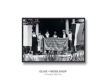 May include: A black and white photograph featuring six individuals standing in a row holding a banner that reads: NO SELF RESPECTING WOMAN SHOULD WISH OR WORK FOR THE SUCCESS OF A PARTY THAT IGNORES HER SEX. SUSAN B. ANTHONY 1872.
