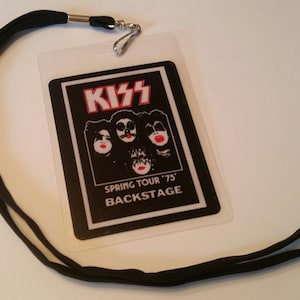 May include: Black and white backstage pass featuring a picture of the band KISS and the text "Spring Tour '75 Backstage". The pass is attached to a black lanyard.