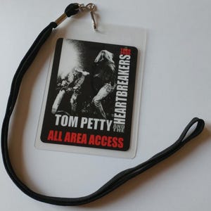 May include: Black lanyard with a clear plastic badge holder featuring a black and white photo of Tom Petty and the Heartbreakers. The badge reads "Tom Petty and the Heartbreakers Tour 2005 All Area Access".