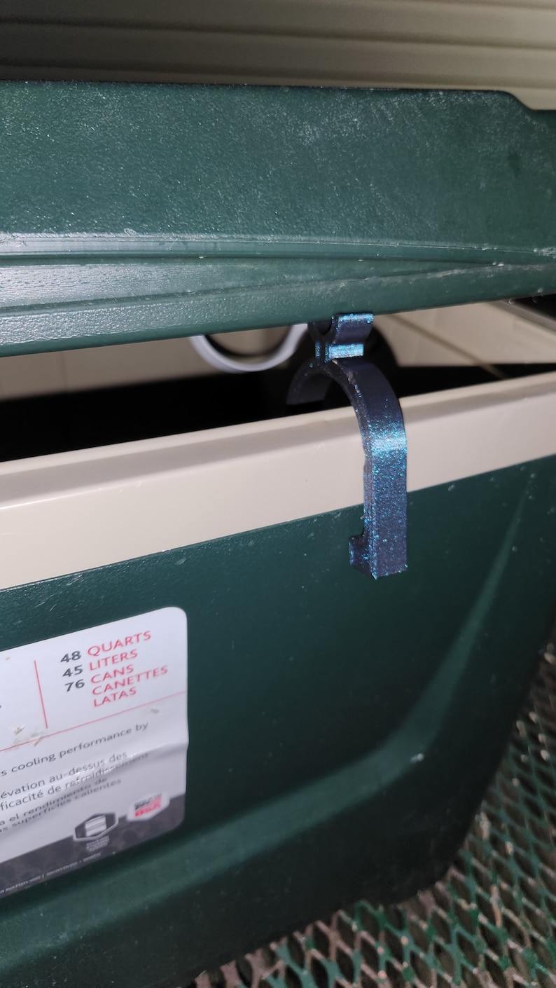 May include: A green cooler with a black latch. The cooler has a label that says "48 Quarts, 45 Liters, 76 Cans, Canettes, Latas".