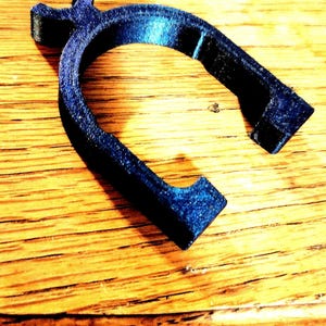 May include: A dark blue plastic ring with a unique design. The ring is made of a smooth, textured plastic and has a slightly curved shape.