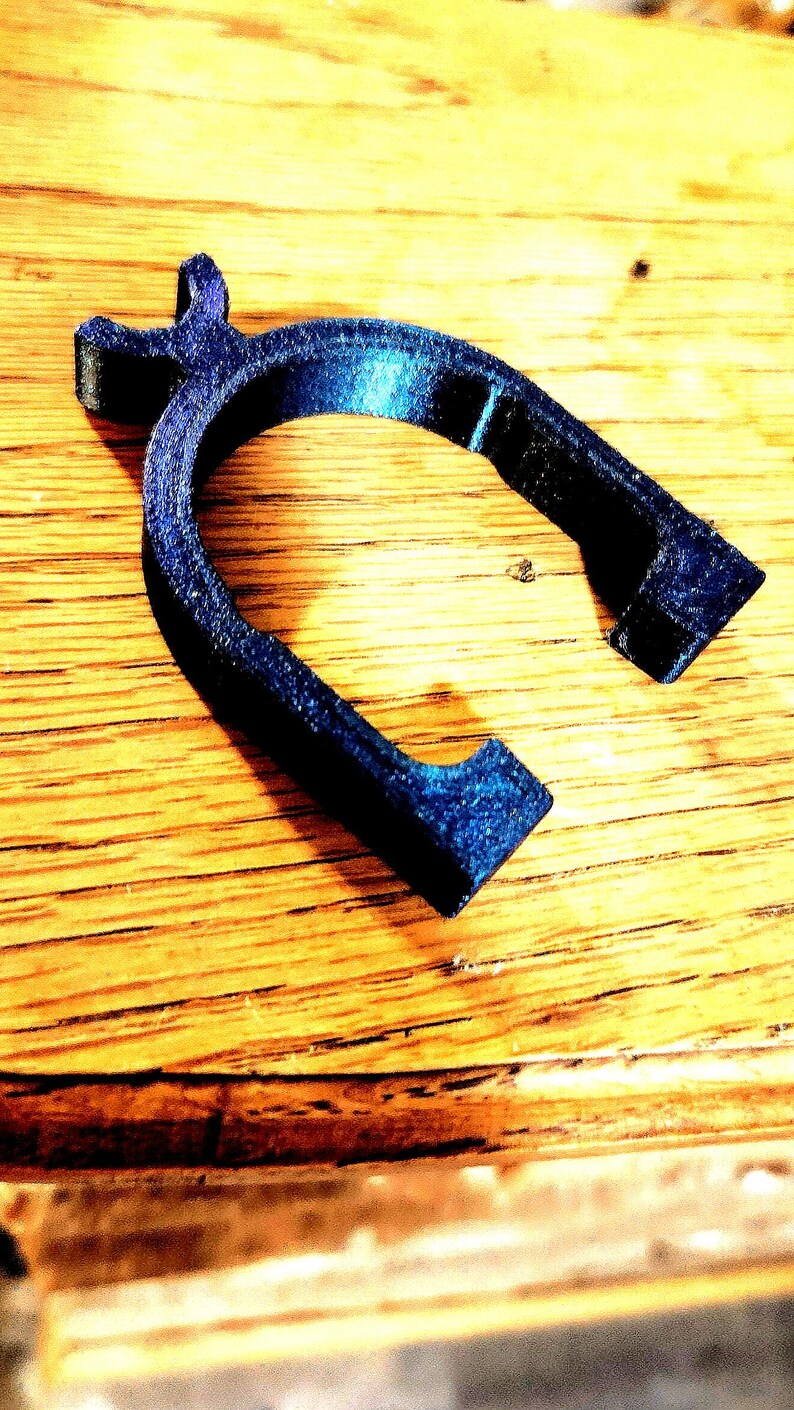 May include: A dark blue plastic ring with a unique design. The ring is made of a smooth, textured plastic and has a slightly curved shape.