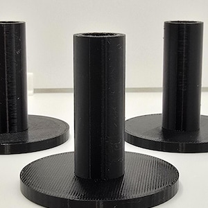 Puede incluir: Tres soportes de exhibición de plástico negro con una base redonda y un poste cilíndrico. Los soportes están hechos con un acabado texturizado.