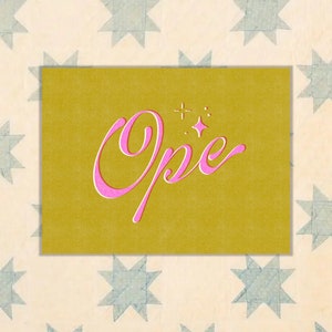 Peut inclure: Une carte jaune avec le mot "Opie" écrit en cursive rose avec une petite étoile au-dessus du mot.