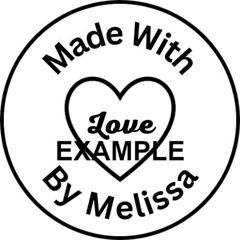 Op de afbeelding: Een ronde zwart-witte sticker met de tekst Made With bovenaan en By Melissa onderaan. In het midden bevat een hartvormige omtrek het woord Love in cursief schrift en het woord EXAMPLE in dikke hoofdletters.