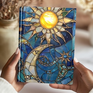 May include: A blue and gold stained glass notebook cover with a sun and moon design. The sun is yellow and the moon is white.