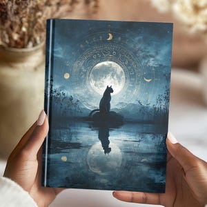 May include: A hardcover journal featuring a mystical design with a full moon, a black cat silhouette, and celestial elements. The cover has a dark blue background with gold accents, creating a magical and enchanting aesthetic.