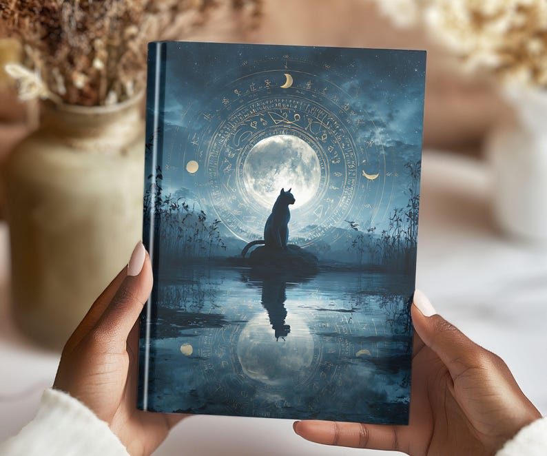 May include: A hardcover journal featuring a mystical design with a full moon, a black cat silhouette, and celestial elements. The cover has a dark blue background with gold accents, creating a magical and enchanting aesthetic.