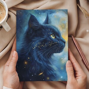 May include: A dark blue cat portrait with a starry night background. The cat's fur is detailed, and golden constellations are depicted on its face. The artwork is held by a person.