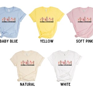 May include: Five t-shirts in baby blue, yellow, soft pink, natural, and white. Each shirt features a graphic of hands and hearts with the text "CELEBRA LA DIVERSIDAD". The shirts are short-sleeved.
