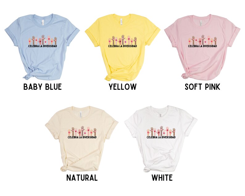 May include: Five t-shirts in baby blue, yellow, soft pink, natural, and white. Each shirt features a graphic of hands and hearts with the text "CELEBRA LA DIVERSIDAD". The shirts are short-sleeved.