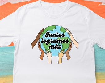 May include: White t-shirt with a graphic of a globe, green continents, and blue oceans, surrounded by hands of different skin tones. The text "Juntos logramos más" is written in black script.