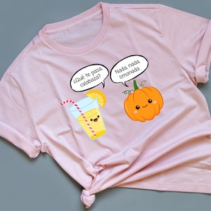 May include: A pink t-shirt with a cartoon glass of lemonade and a pumpkin with the text "¿Qué te pasa calabaza?" and "Nada nada limonada."