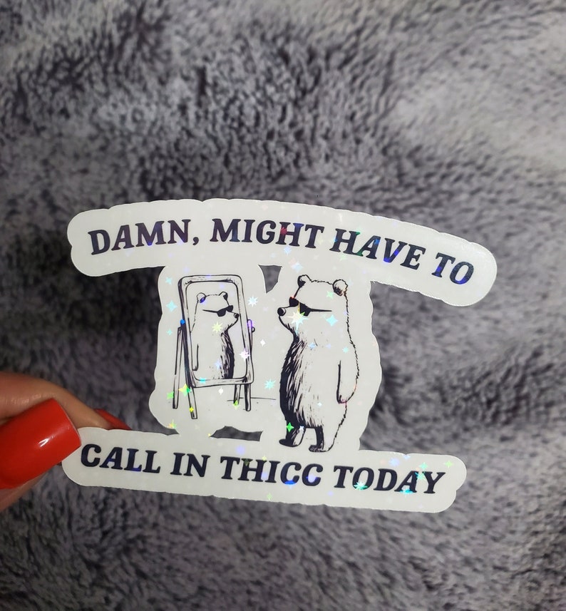 May include: A white sticker with a holographic finish features a cartoon bear wearing sunglasses and looking at its reflection in a mirror. The text on the sticker reads "DAMN, MIGHT HAVE TO CALL IN THICC TODAY."