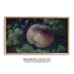 May include: A still life painting of a peach and grapes. The peach is in the center of the painting and is a light pink color. The grapes are green and purple and are arranged around the peach. The painting is framed in a wooden frame.