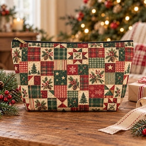 May include: A zippered pouch featuring a patchwork design of holiday-themed fabric squares. The pattern includes illustrations of evergreen trees, holly berries, pinecones, stars, and snowflakes in a color palette of deep red, forest green, and cream.