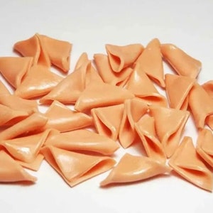 May include: A pile of approximately 25 small, triangular, peach-colored, crispy snacks.