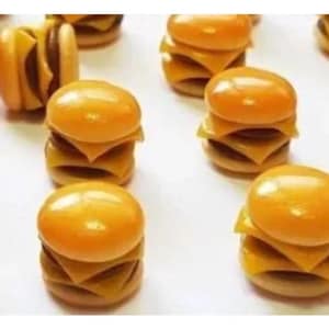 May include: A collection of miniature, yellow and brown, double-decker cheeseburger-shaped polymer clay charms.