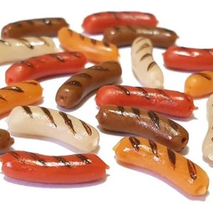 May include: A collection of miniature plastic hot dogs in various colors, including brown, orange, white, and red. Some of the hot dogs have grill marks.