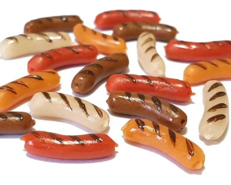 May include: A collection of miniature plastic hot dogs in various colors, including brown, orange, white, and red. Some of the hot dogs have grill marks.