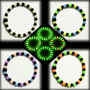 May include: Five glow-in-the-dark bracelets in different colors. The bracelets are made of round beads and have a black bead at the end of each bracelet.