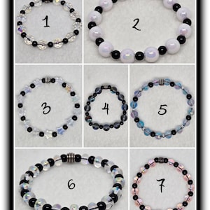 Può includere: Sette braccialetti diversi con perline nere e bianche. I braccialetti sono numerati da 1 a 7.