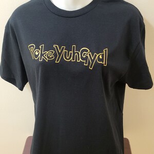 May include: Black t-shirt with a gold outline of the text "PokeYuhGyal" on the front.