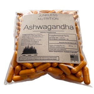 May include: A transparent bag containing numerous orange capsules. The label reads "Junkless Nutrition Ashwagandha Dietary Supplement." The label provides supplement information and usage instructions. The capsules are for dietary use.