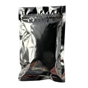May include: A shiny, silver metallic pouch with a zip-top closure. The pouch is empty and has a reflective surface, creating highlights and shadows. The packaging is designed to protect the contents.