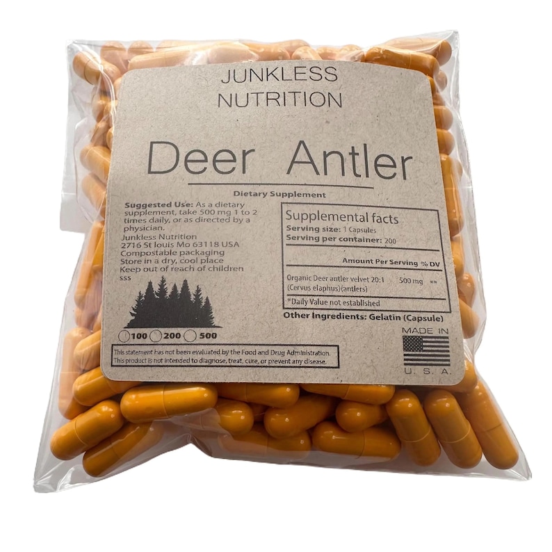 以下が含まれることがあります： オレンジ色のカプセルが入った透明なビニール袋。袋には「Junkless Nutrition Deer Antler Dietary Supplement」と書かれたラベルが付いています。ラベルには栄養成分表示と使用方法が記載されています。カプセルは栄養補助食品です。