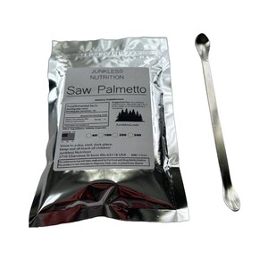 May include: A silver foil packet of "Saw Palmetto" dietary supplement capsules with a silver metal scoop. The packet has a white label with black text, including "Junkless Nutrition" and dosage information. The scoop is long and slender.