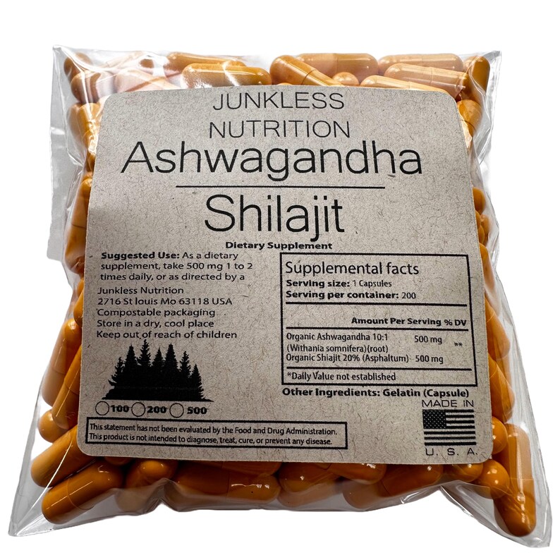 May include: A clear plastic bag filled with orange capsules. The bag has a label with the words "Junkless Nutrition Ashwagandha Shilajit Dietary Supplement." The label includes supplement facts and suggested use information.