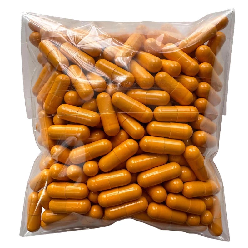 May include: A clear plastic bag filled with numerous orange capsules. The capsules are cylindrical with rounded ends, and appear to be filled with a powder. The bag is transparent, allowing a full view of the capsules.
