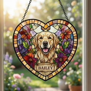 May include: Stained glass heart-shaped suncatcher featuring a Golden Retriever dog portrait. The design includes colorful flowers, a butterfly, and the name "BAILEY" on a banner. The suncatcher hangs from a black chain.