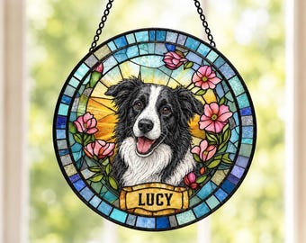 May include: A circular stained glass suncatcher featuring a black and white Border Collie portrait. The dog is surrounded by pink flowers and a yellow sunburst background. A gold banner at the bottom displays the name LUCY in black letters.