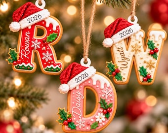 May include: Three hanging letter ornaments shaped like cookies with white icing, red Santa hats, and the year 2026. The letters R, D, and W are personalized with the names Rowan, Daisy, and Wyatt, decorated with green holly leaves and red berries.