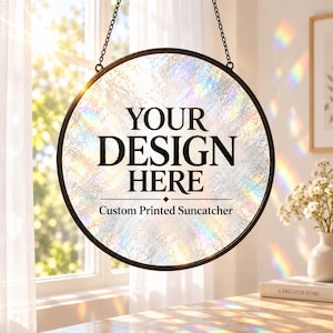May include: A circular suncatcher with a dark metal frame and a textured, iridescent glass surface. The center features the black text "YOUR DESIGN HERE" above the words "Custom Printed Suncatcher" and a small diamond icon.