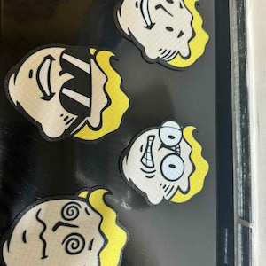 May include: Four cartoon face stickers with various expressions. Each sticker features a white face with black outlines and yellow hair. The expressions include a smile, a surprised look, and a confused look.