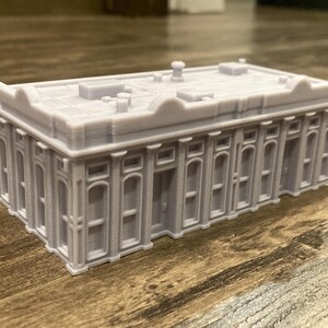 Pu&ograve; includere: Un modello grigio dettagliato di un edificio con un tetto piatto e molte finestre. Il modello &egrave; in plastica e ha una finitura liscia.