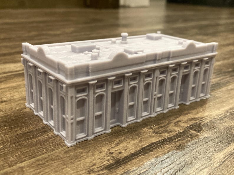 Pu&ograve; includere: Un modello grigio dettagliato di un edificio con un tetto piatto e molte finestre. Il modello &egrave; in plastica e ha una finitura liscia.