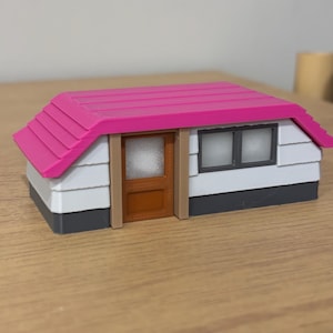 May include: A miniature model of a house featuring a bright pink roof, white horizontal siding, a brown door with a textured panel, and a rectangular window with a dark gray frame. The base of the structure is a solid dark gray color.