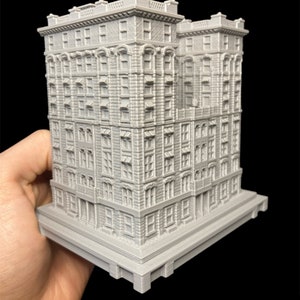 K&ouml;nnte beinhalten: Ein detailliertes, graues 3D-gedrucktes Modell eines hohen, schmalen Geb&auml;udes mit mehreren Fenstern und einem dekorativen Gesims. Das Geb&auml;ude hat einen Sockel mit einer strukturierten Oberfl&auml;che.