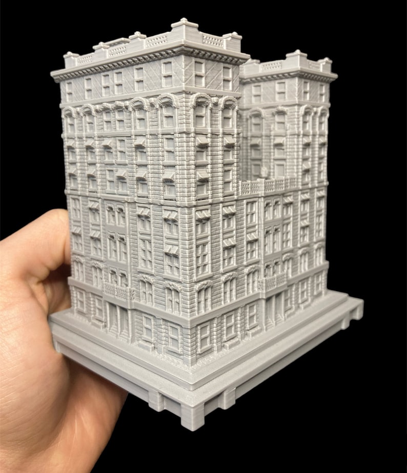K&ouml;nnte beinhalten: Ein detailliertes, graues 3D-gedrucktes Modell eines hohen, schmalen Geb&auml;udes mit mehreren Fenstern und einem dekorativen Gesims. Das Geb&auml;ude hat einen Sockel mit einer strukturierten Oberfl&auml;che.