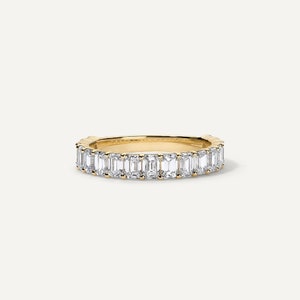 May include: A gold band ring with a row of emerald-cut diamonds.