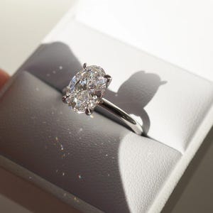 May include: A silver ring with a large, oval-shaped diamond.