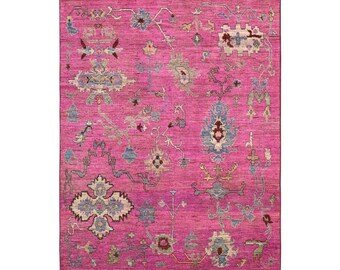 May include: A pink rug with a traditional Persian design featuring intricate floral and geometric patterns in shades of blue, beige, and red.