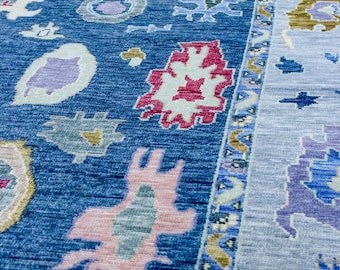 May include: A blue and light blue rug with a geometric pattern. The rug has a border with a repeating pattern of small flowers and leaves.