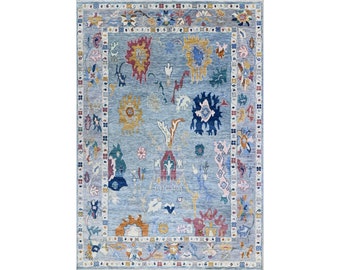 May include: A blue rug with a floral pattern in shades of pink, yellow, red, and blue. The rug has a border with a geometric pattern.