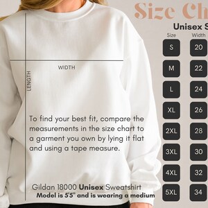 May include: A white Gildan 18000 unisex sweatshirt with a size chart. The chart lists sizes S-5XL with width and length measurements in inches. The text advises comparing measurements to a garment. Model is 5'5" and wearing a medium.